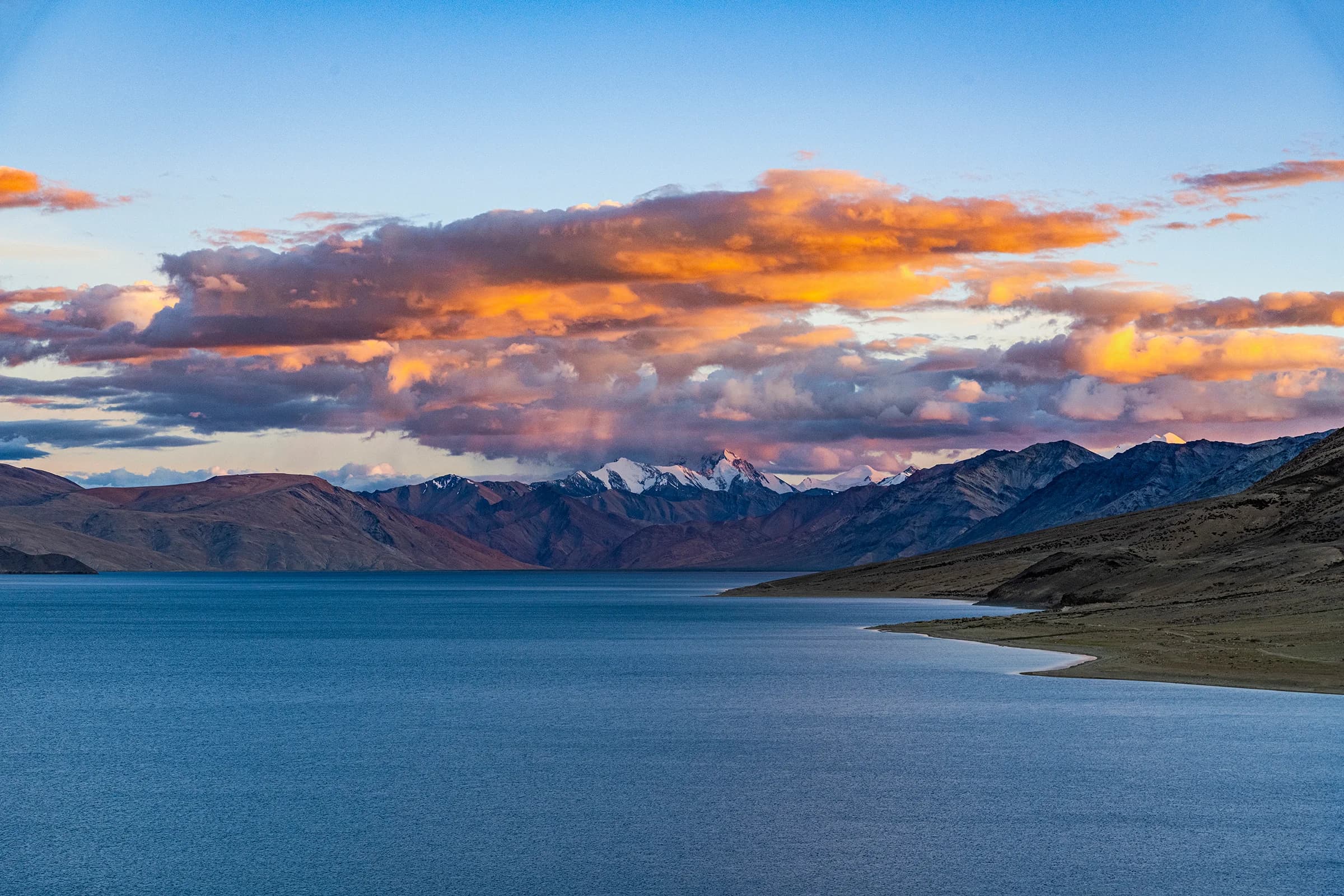 Mountain lake beneath glowing clouds in Ladakh